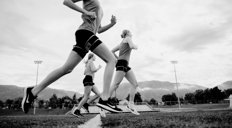 Girls running on a field with BFR bands